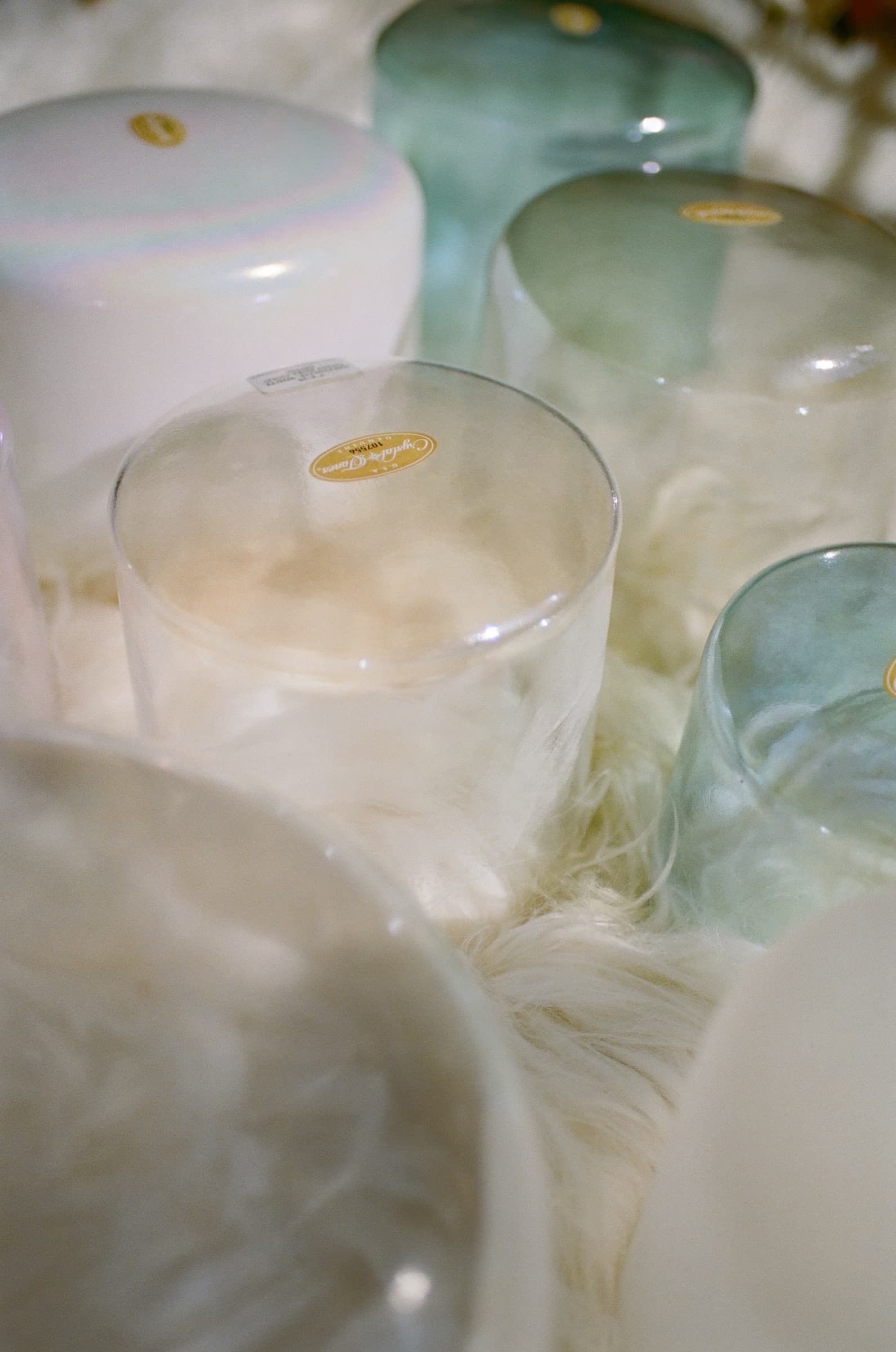 Crystal singing bowls in soft pastel tones resting on a sheepskin rug