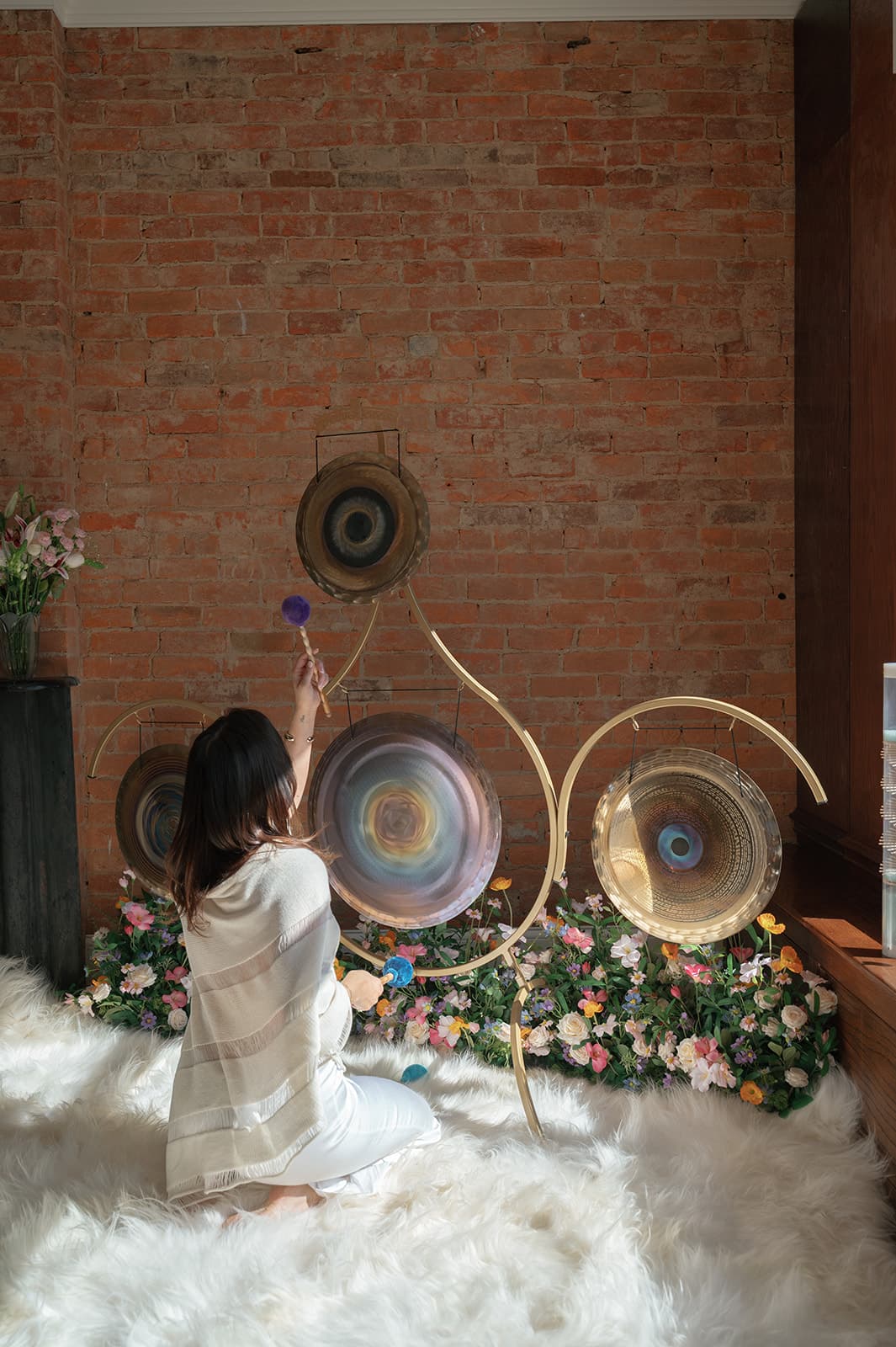 Laura playing a wall of gongs in her studio