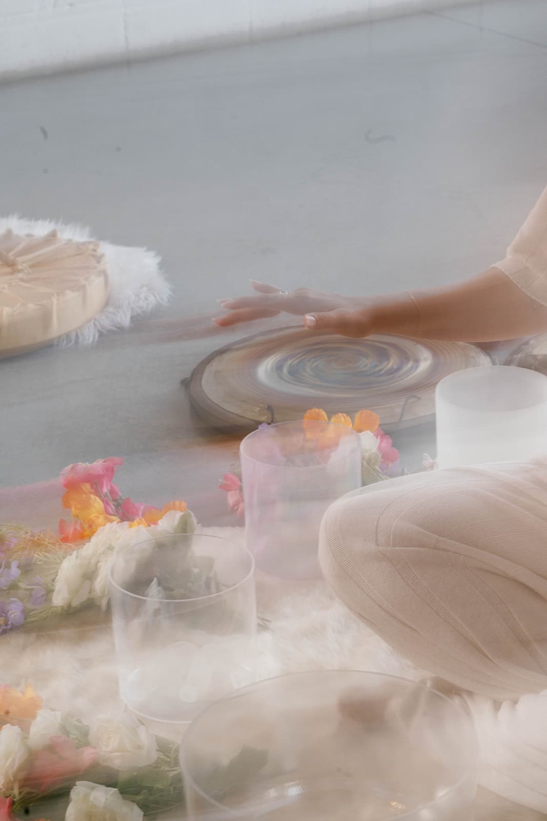 Soft-focus view of a sound bath setup with bowls and flowers on the floor