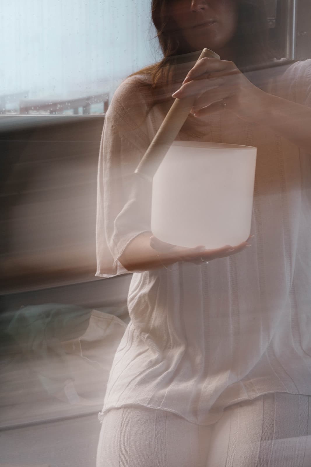 Soft-focus photo of Laura carrying a crystal singing bowl through the studio